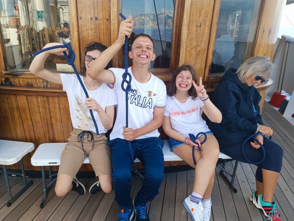 Gruppo di ragazzi sorridenti che stanno facendo i nodi marinari a bordo di Nave Italia - Campagna 2023
